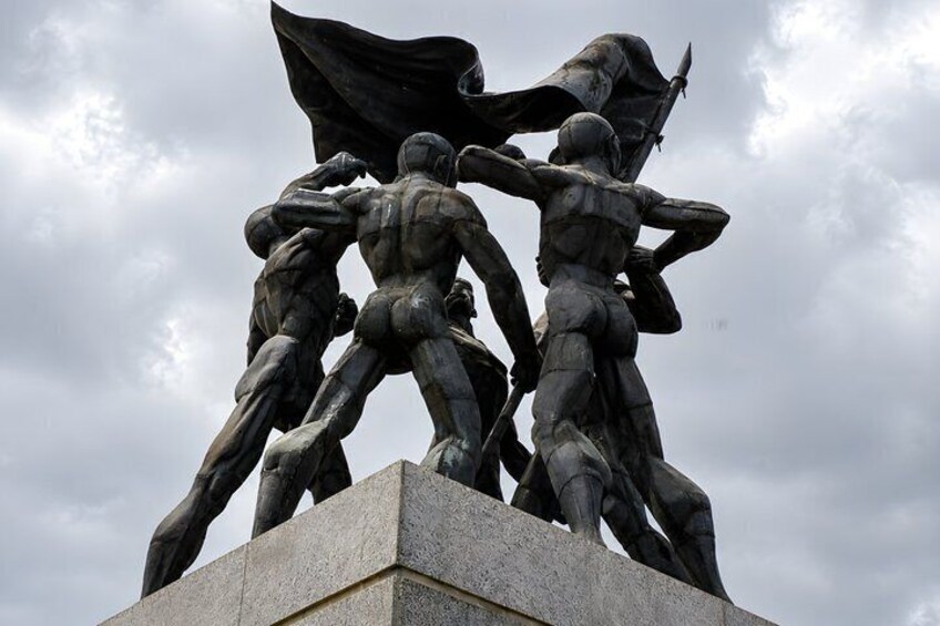 A sculpture of figures in dynamic poses on a pedestal. 4
