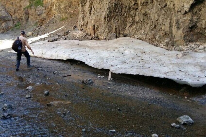 A person walking near a large ice formation in a rocky terrain. 4