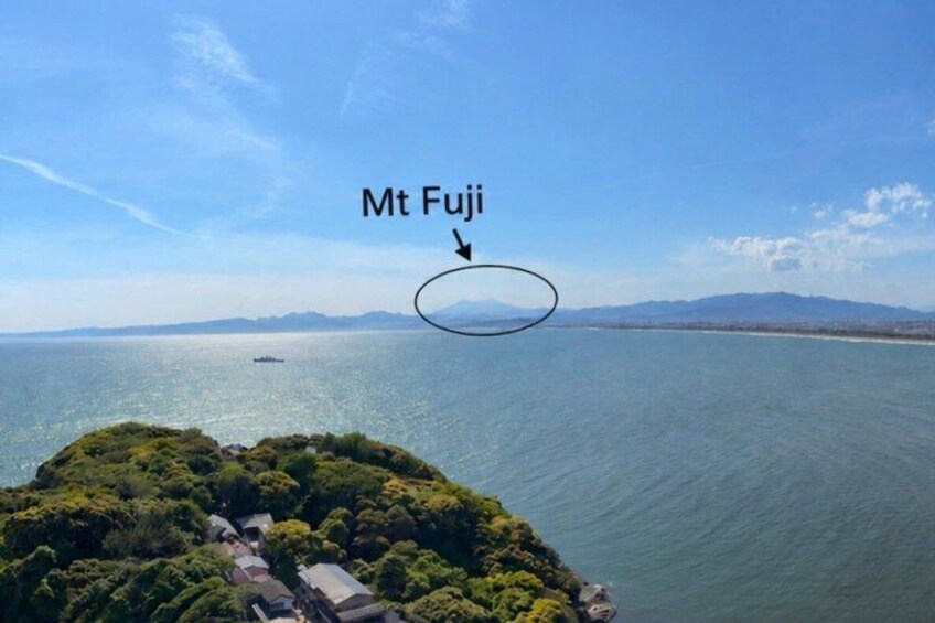 Mt Fuji, a prominent mountain in the background, with a view of the sea and a small island with buildings in the foreground. 5