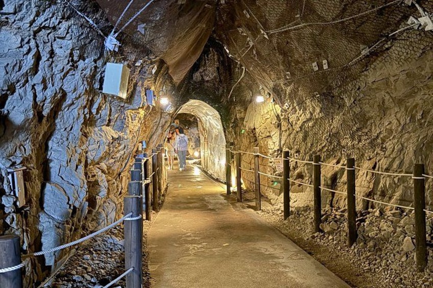 A cave tunnel with wooden railings and a concrete path. 3