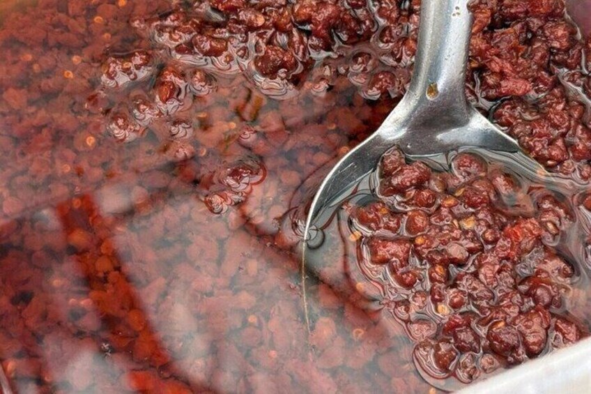 A close-up of a spoon scooping a thick, reddish-brown substance, likely a type of sauce or condiment. 3
