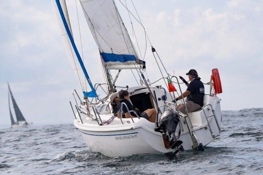 A sailboat with two people on deck, one steering and one looking out. 3