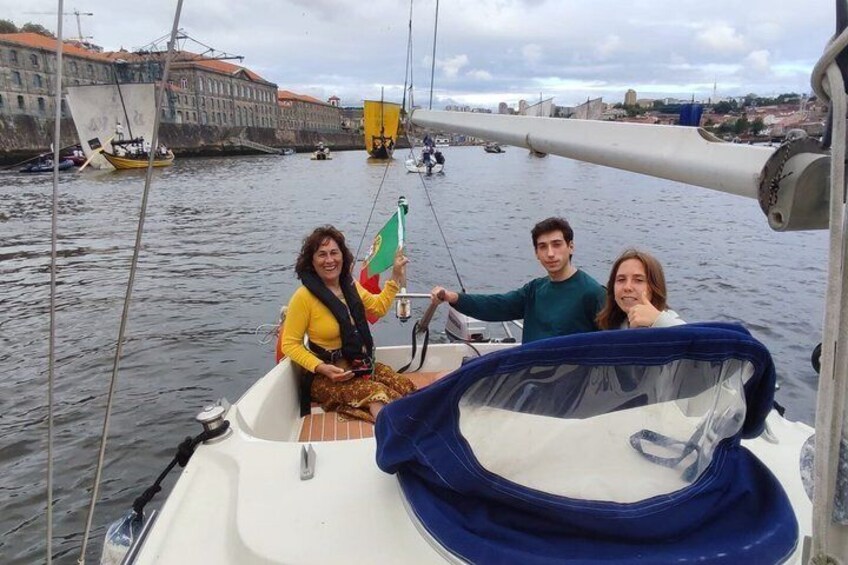 A boat with three people on a river, a cityscape in the background, and a bridge. 2
