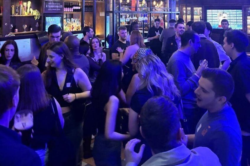 A crowded bar with people socializing and dancing. 2