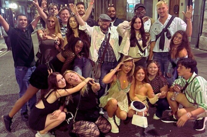 A group of people posing for a photo on a city street at night. 2