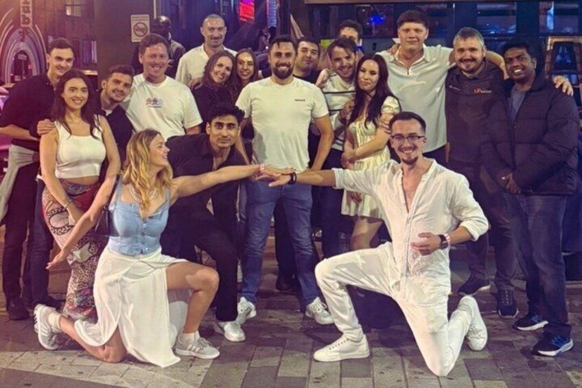A group of people posing for a photo in an urban setting with buildings and street lights in the background. 3