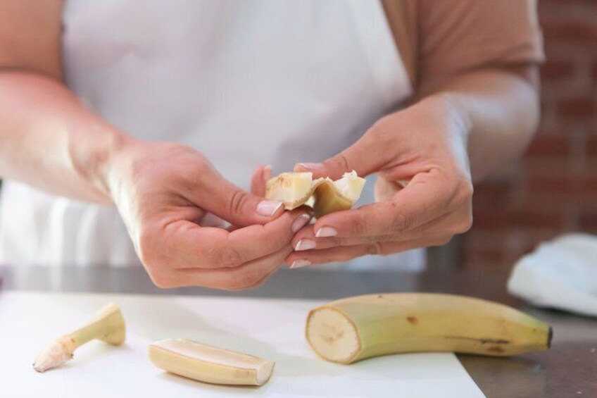 A person peeling a banana on a white cutting board. 5