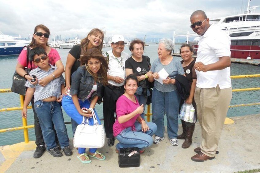 A group of people posing by a waterfront with boats in the background. 5