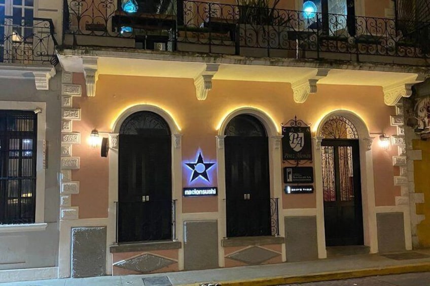 A building with three arched doors, a neon sign, and a star logo. 3