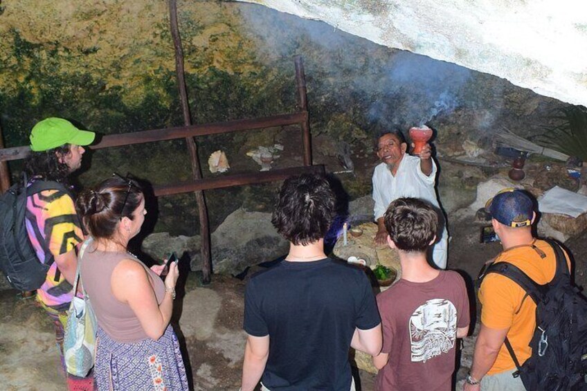 A group of people observing a cooking demonstration inside a cave. 3