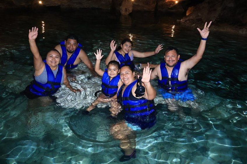 People in blue life vests in a clear water body, possibly a pool or a natural water feature. 4