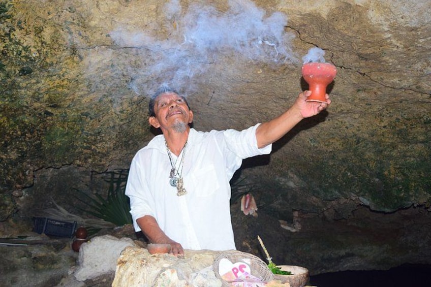 A person holding a red object emitting smoke in a cave. 2