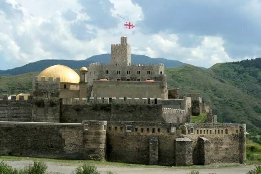 A historic castle with a golden dome and a flag atop the central tower. 3