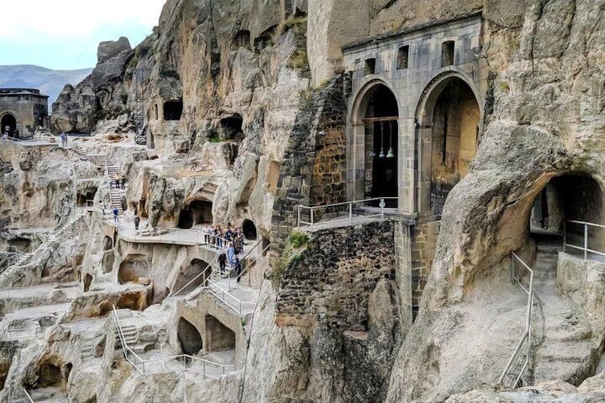 A rock-hewn monastery with arched doorways and staircases carved into the rock. 1