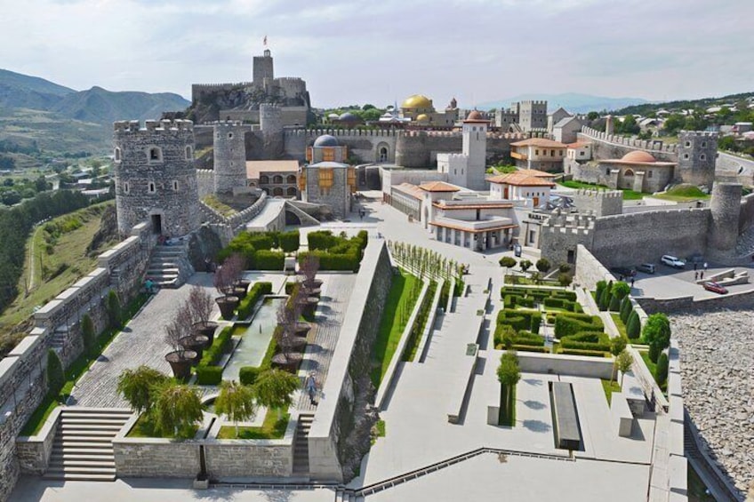 A historic fortified city with a castle, walls, and a well-maintained garden. 5