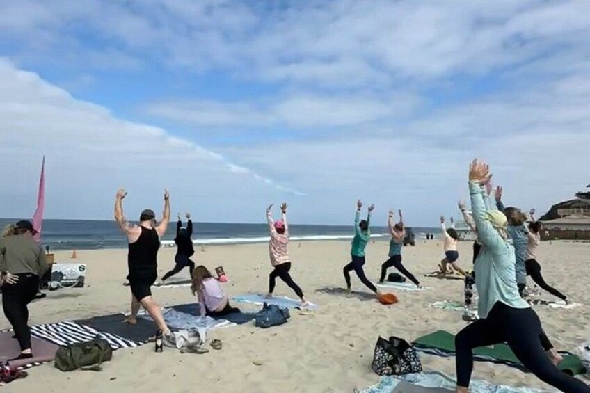 A group of people performing a synchronized exercise routine on a beach. 5