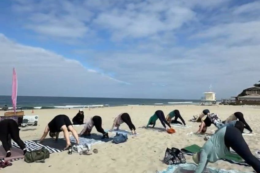 People stretching on a beach with umbrellas and a lifeguard tower in the background. 4