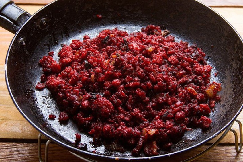 A frying pan with a red, textured food mixture. 2