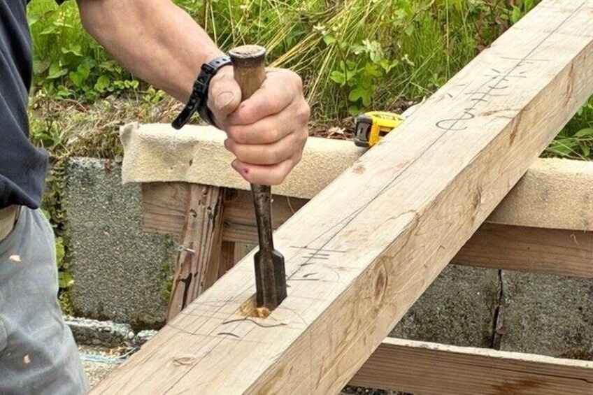 A person hammering a nail into a wooden beam. 1
