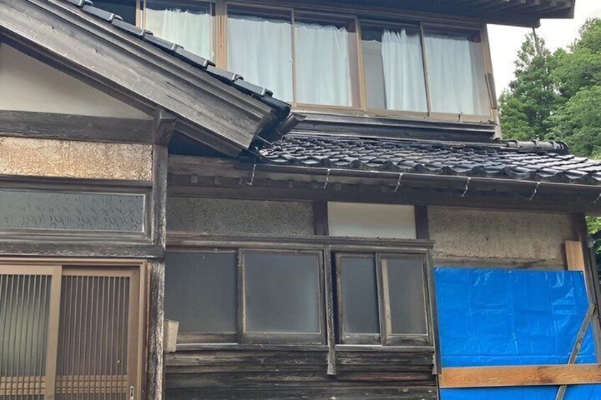A traditional Japanese building with a partially damaged roof and blue tarp covering part of the structure. 4