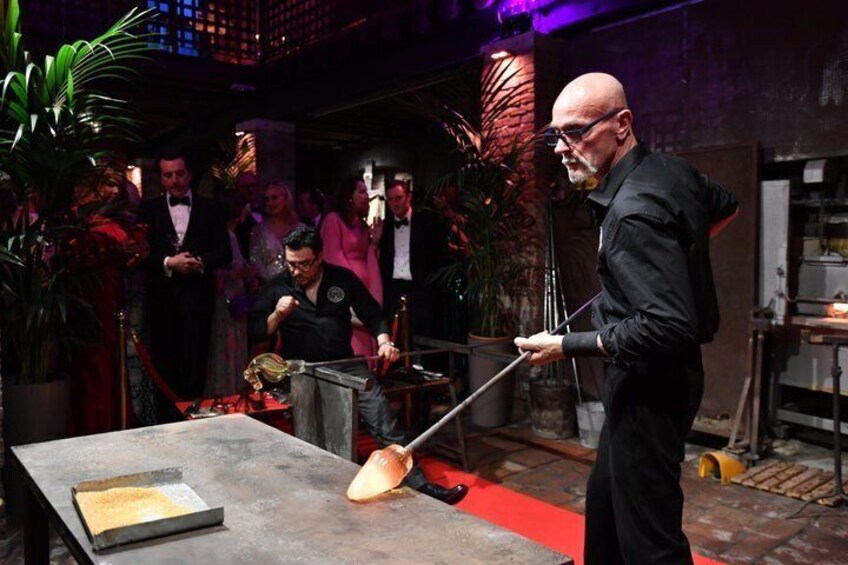 A person performing a metalworking task with a torch, surrounded by onlookers. 5