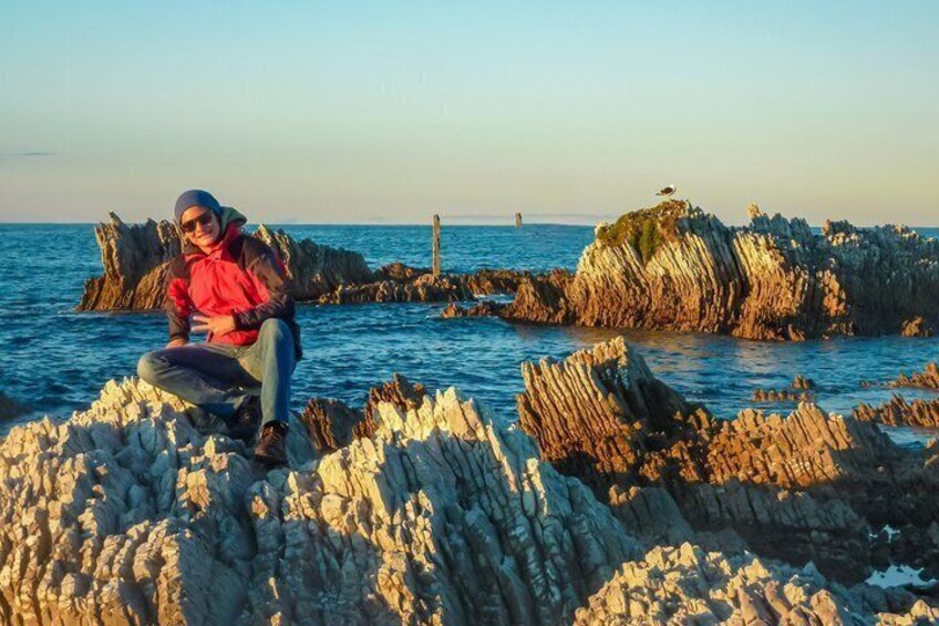 A person sitting on rocky formations by the sea. 4