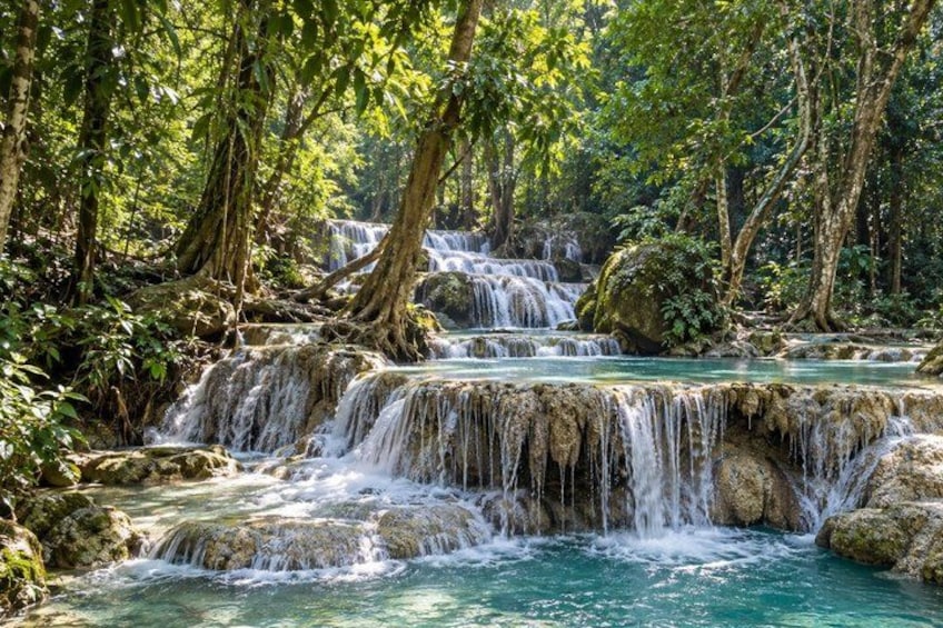A multi-tiered waterfall in a forested area with rocky formations and dense greenery. 5