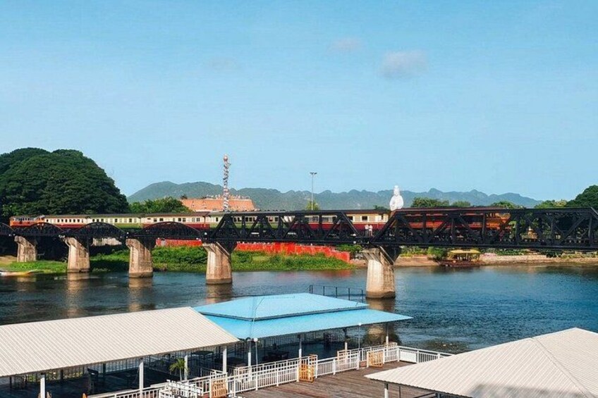 A bridge over a river with a train on it, a statue, and a building in the background. 4