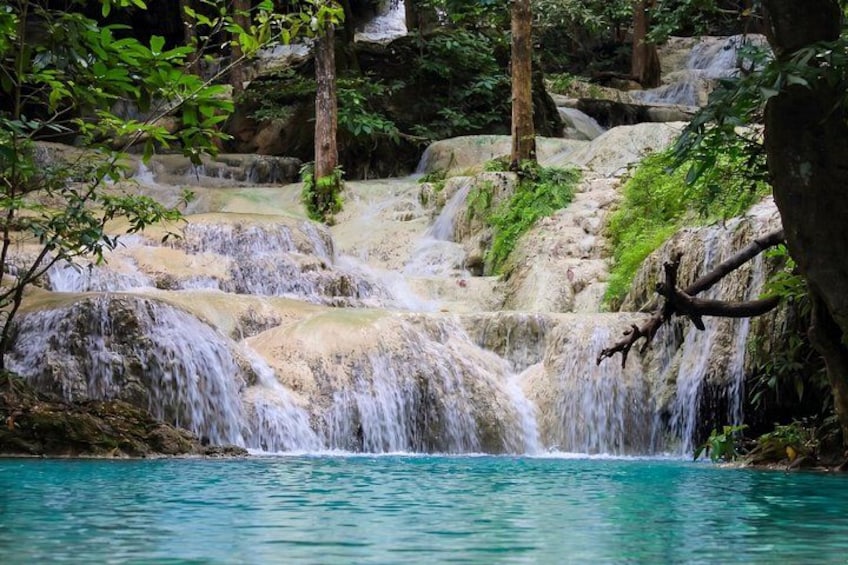 A waterfall cascading over rocks into a turquoise pool surrounded by greenery. 5