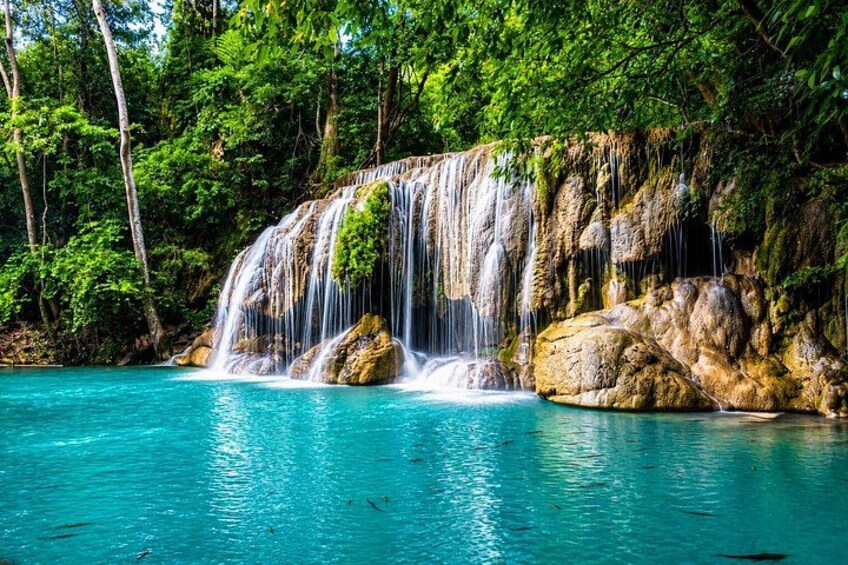 A waterfall cascading over rocks into a turquoise pool surrounded by lush greenery. 1