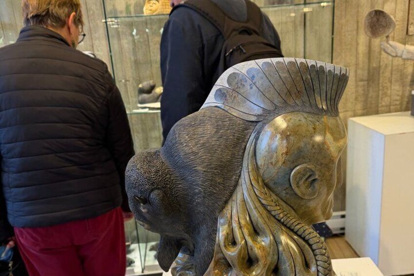 A sculpture of a fish with a human-like face, displayed in a museum. 4