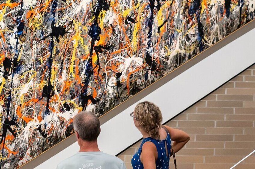 Two people observing a large abstract painting on a wall. 3