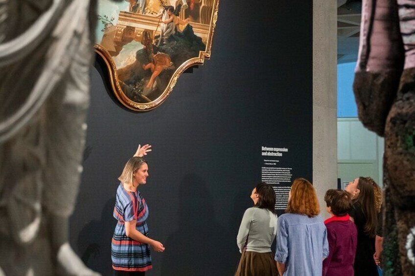 A group of people observing a framed artwork on a wall. 4