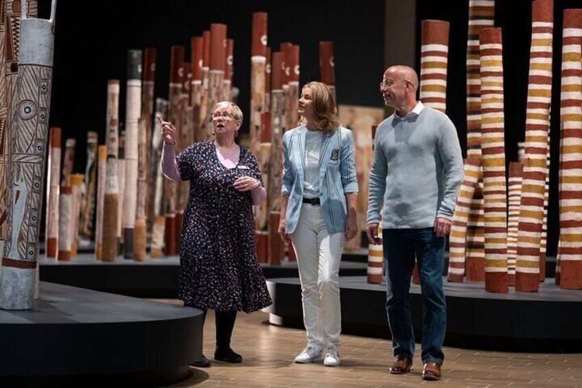 A museum exhibit with wooden sculptures and a person gesturing. 1
