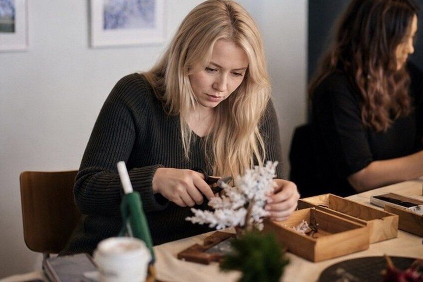 A person sitting at a table with a plant, a cup, and a box. 3