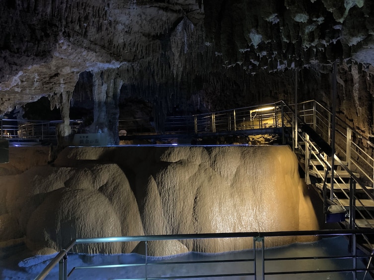 Una cueva con estalactitas, una gran formación rocosa y escaleras metálicas que conducen a una plataforma de observación. 4
