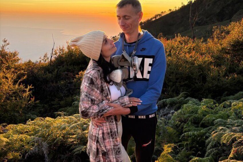A couple embracing on a hillside with a sunset in the background. 5