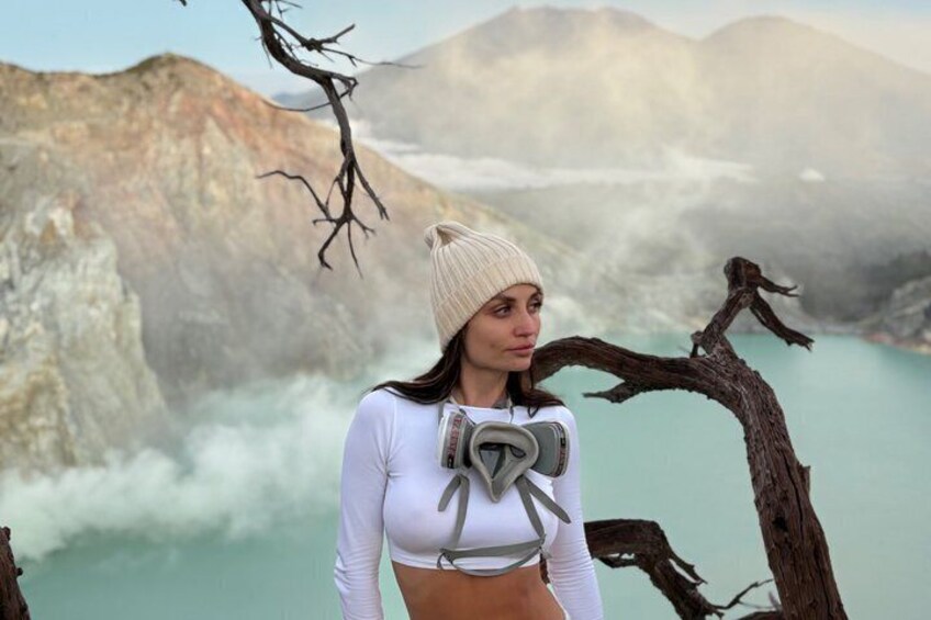 A person standing by a tree with a mountainous landscape in the background. 5