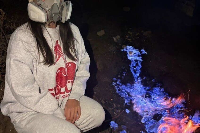 A person sitting by a campfire at night. 2