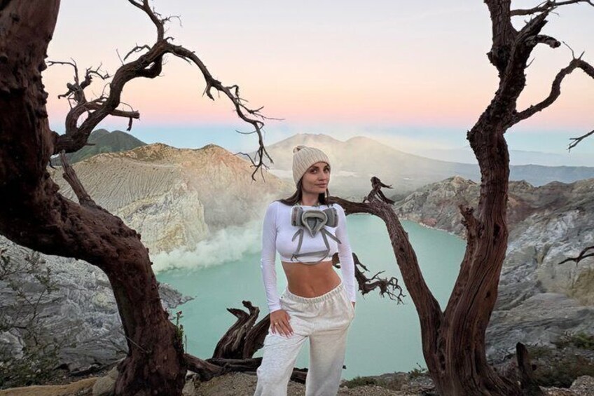 A person standing between two trees with a mountainous landscape in the background. 4