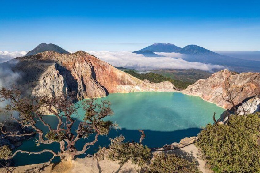 A volcanic crater lake surrounded by rugged terrain and distant mountains. 1