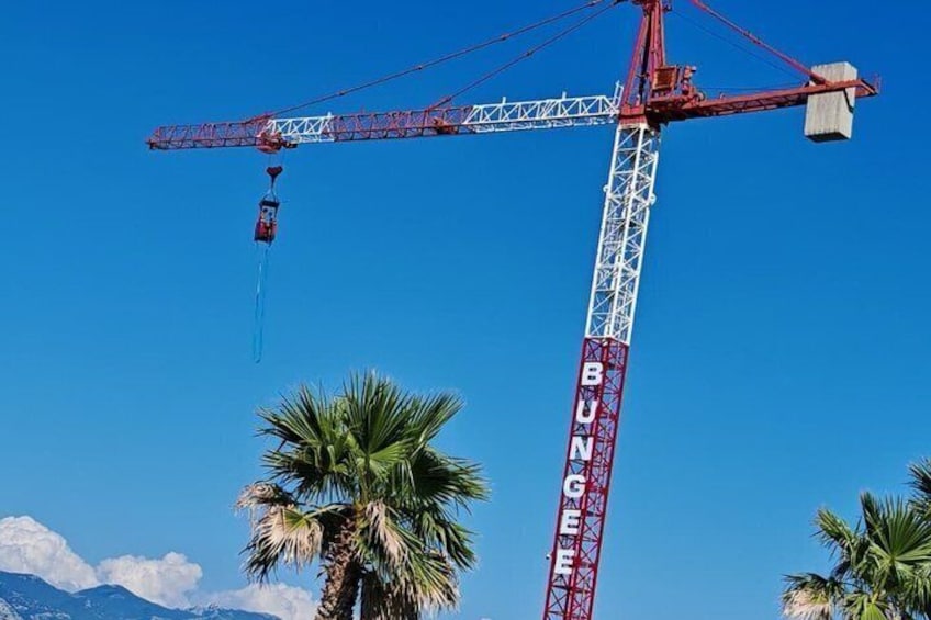 A red crane with 'BUNGEE' written on it, palm trees, and a clear blue sky. 3