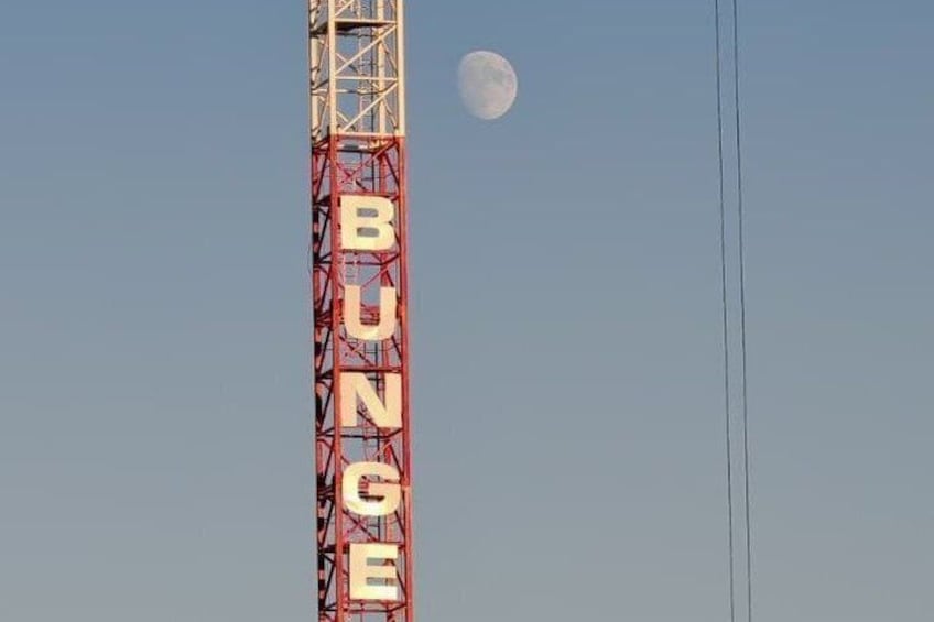 A tall structure with the word 'BUNGE' on it, a clear sky, and the moon in the background. 2
