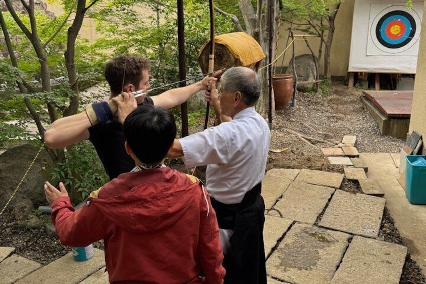 An outdoor archery activity with participants aiming at a target. 1