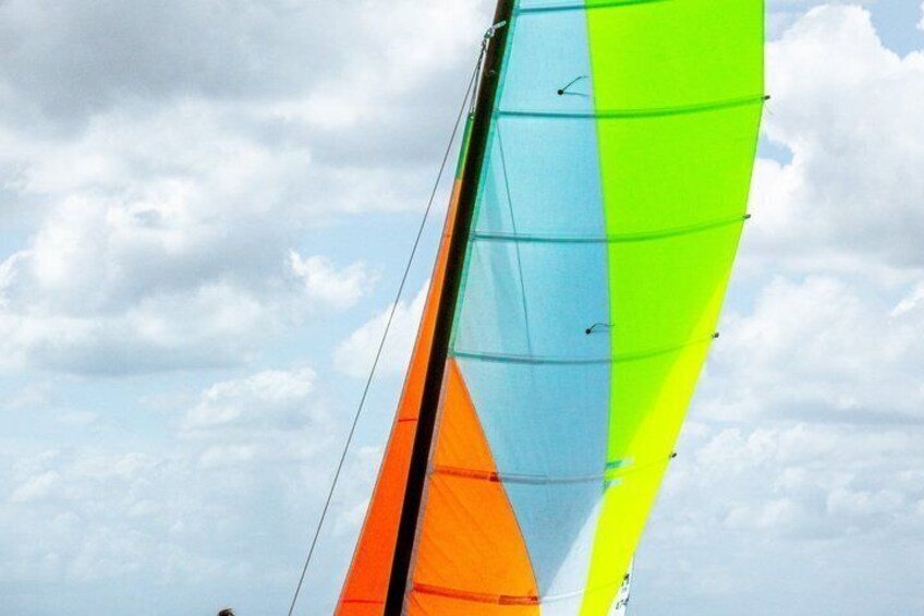 A colorful sailboat with a multicolored sail against a cloudy sky. 4