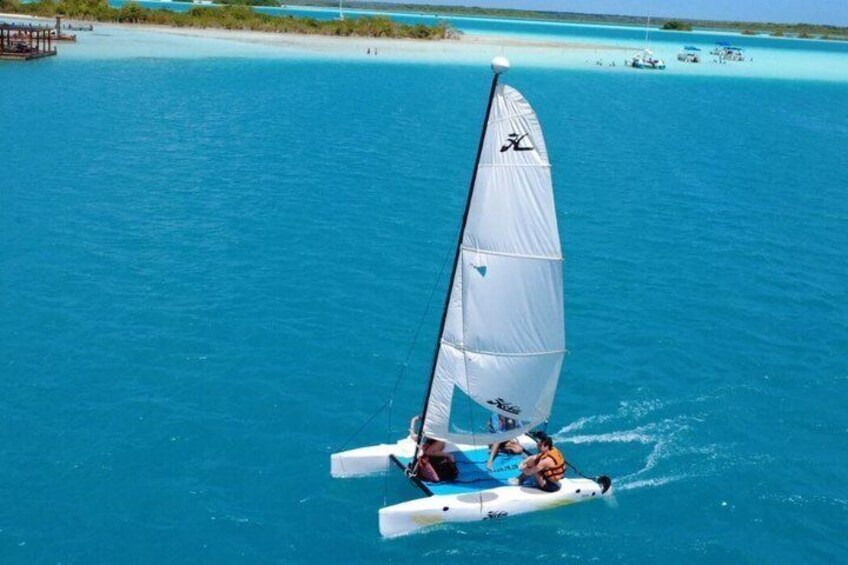 A person sailing a catamaran on turquoise waters with a clear sky. 1