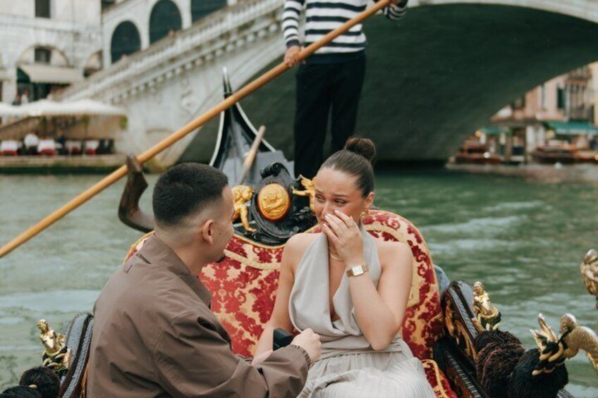 A gondola with a man and a woman, a bridge, and a canal in the background. 1