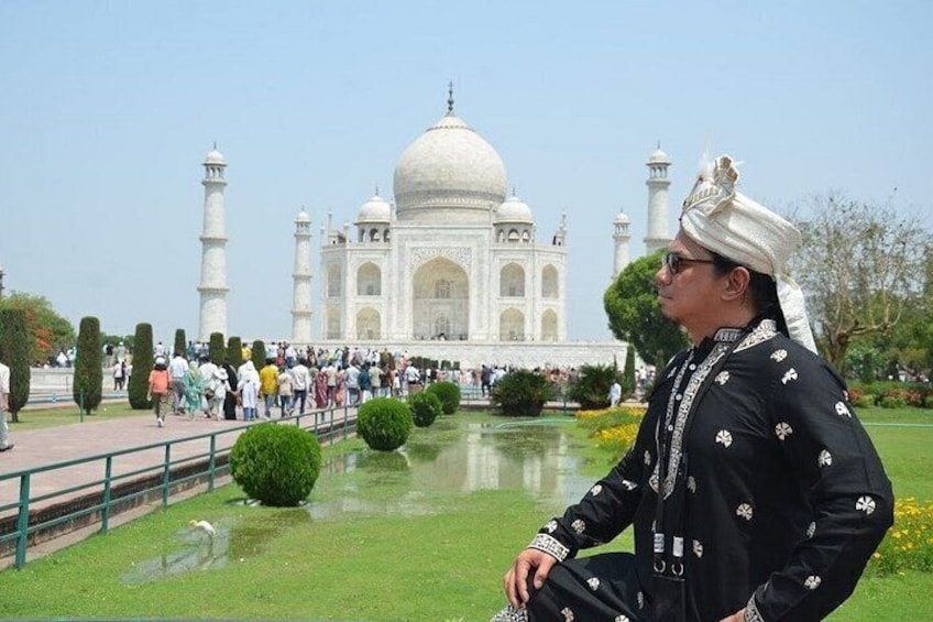 A person in traditional attire, the Taj Mahal, and a crowd of visitors. 3