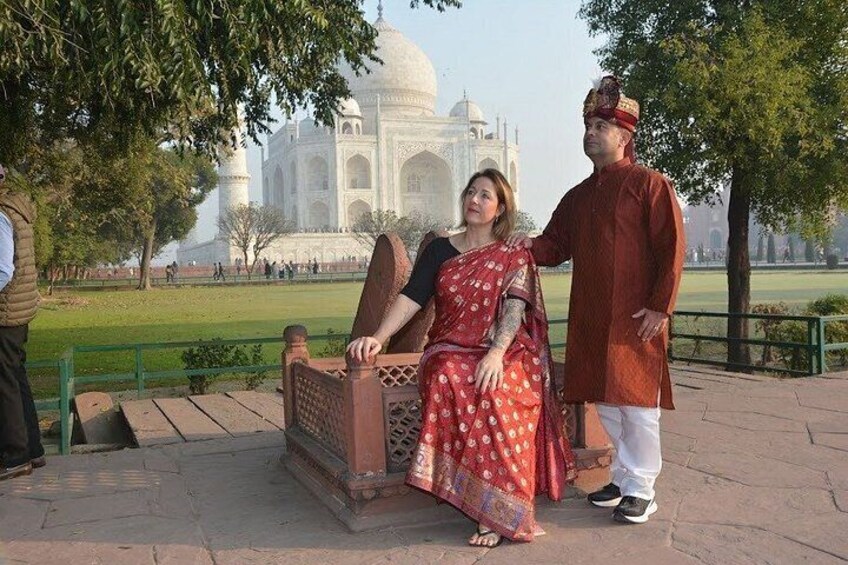 A couple sitting on a bench with the Taj Mahal in the background. 5