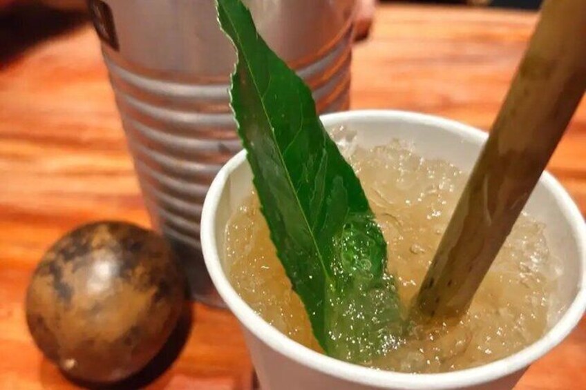 A cup of iced tea with a green leaf and a wooden spoon. 4